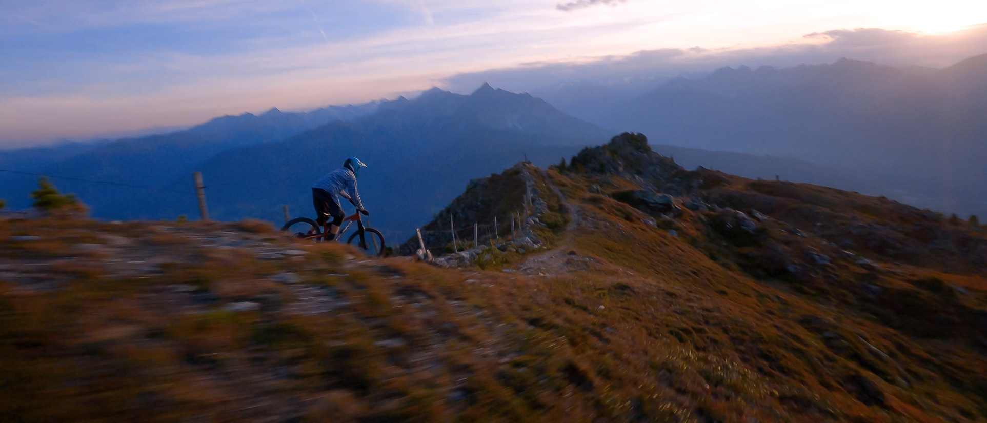 Ein Mountainbiker fährt in den Sonnenuntergang in den Bergen.