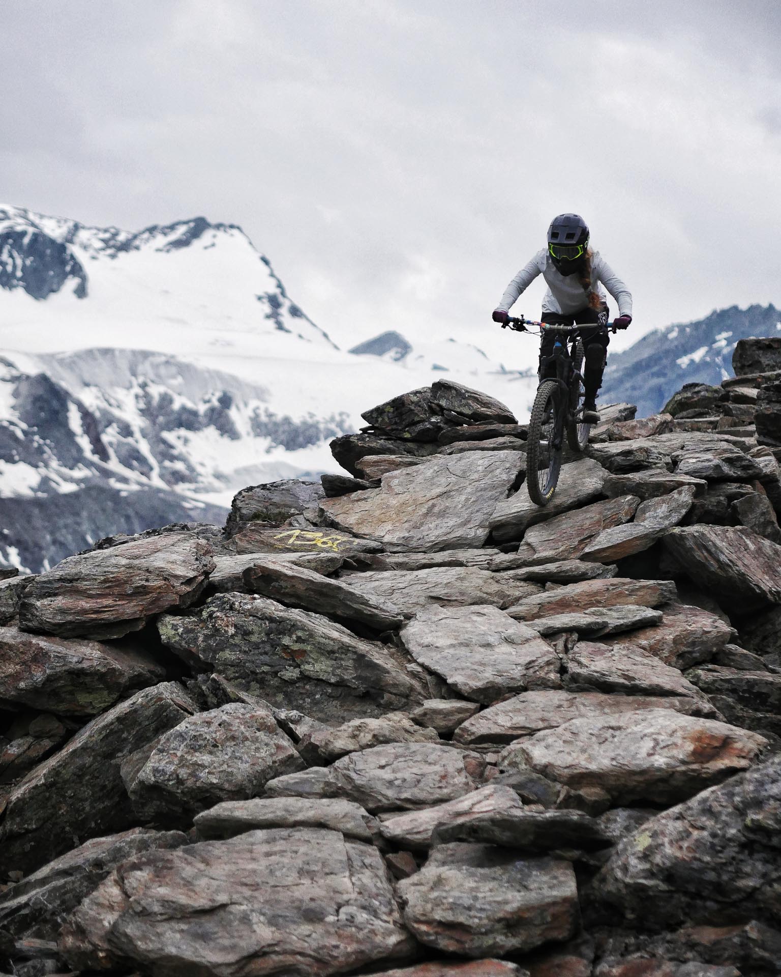 Eine Mountainbikerin fährt durch ein Steinfeld im alpinen Sölden, Österreich.