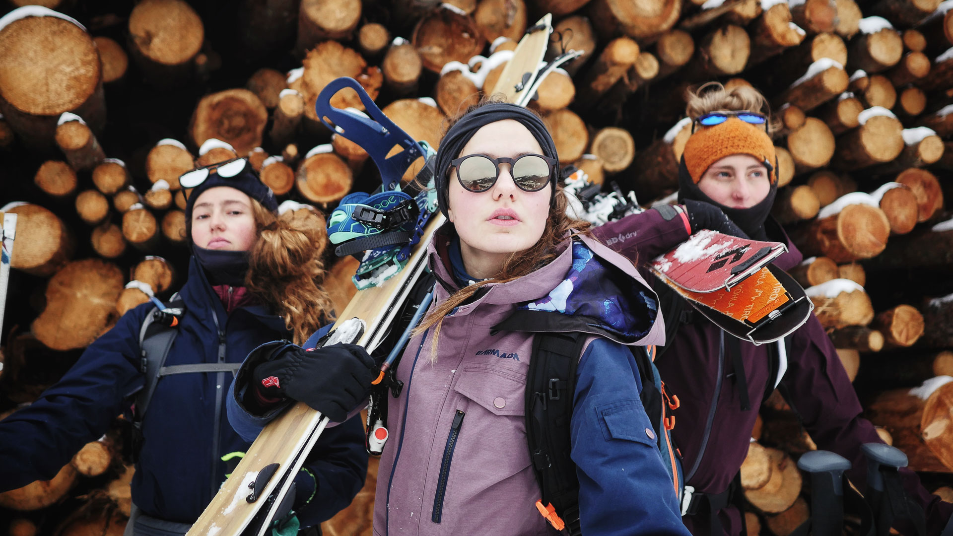 Three snowboarder girls are ready for a ski tour with their splitboards and skis.