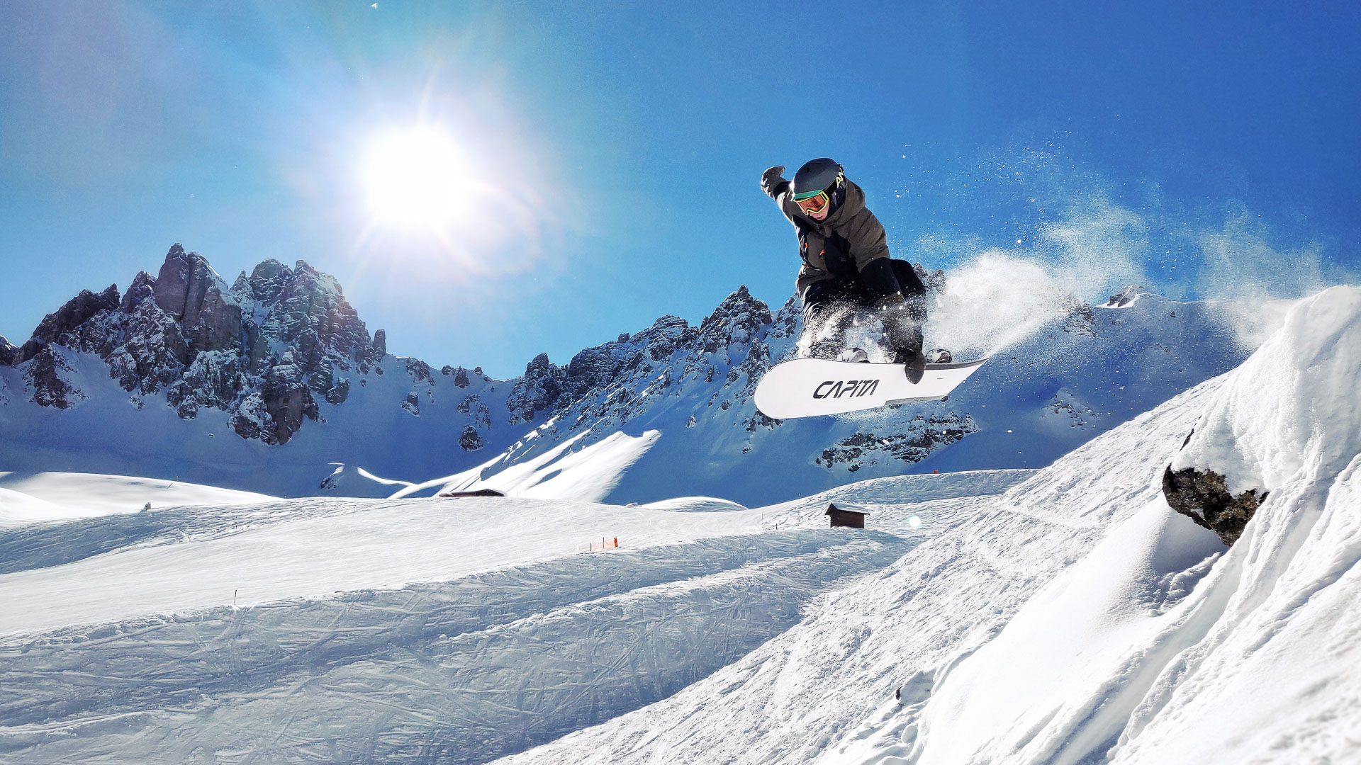 Ein Snowboarder springt beim Freeriden durch den Tiefschnee in Innsbruck.